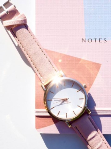 Montre rose posée sur un carnet de notes, symbole du temps dédié à l’accompagnement et à l’écriture