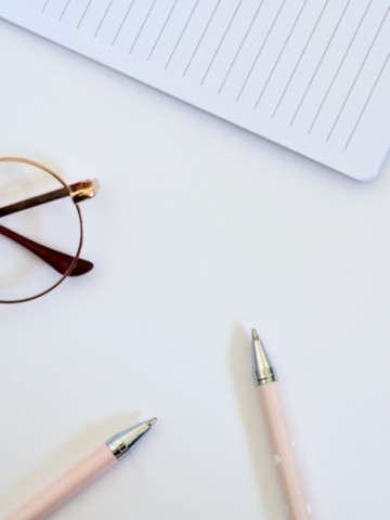 Stylos, lunettes et carnet — correction de manuscrit