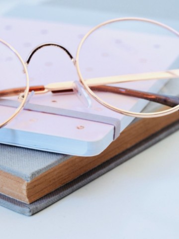 Clarté du propos, respect de la voix. "Lunettes dorées posées sur un carnet clair, symbolisant la précision et la réflexion littéraire